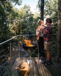 格倫科的住宿－RiverBeds - Luxury Wee Lodges with Hot Tubs，两个人站在烧烤架旁边的甲板上