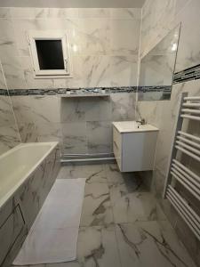 y baño con bañera, lavabo y espejo. en appartement luxueux 70m2, 2 chambres, en Argenteuil