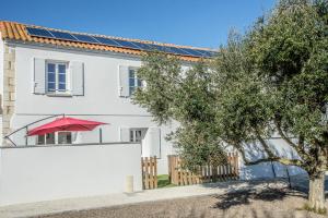 una casa blanca con un paraguas rojo y una valla blanca en LE COMMODORE Maison avec piscine/parking/wifi/plages 5kms en Les Mathes