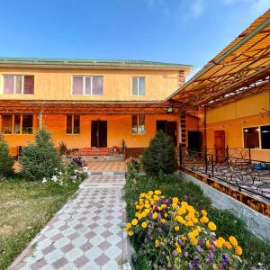 a courtyard of a building with flowers in front of it at Guest House Jekshen in Imeni Karla Marksa