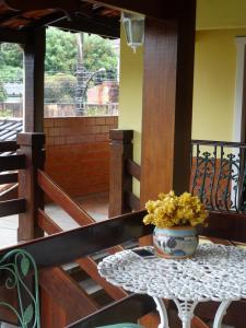 a table with a vase of flowers on a porch at Pousada Azaléia in Rio das Flores