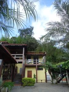 una casa con una palmera delante de ella en Pousada Azaléia, en Rio das Flores