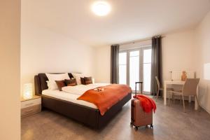 ein Schlafzimmer mit einem Bett mit einem Koffer und einem Schreibtisch in der Unterkunft Hotel & Boarding House Schlosserwirt in Mering + 37 Fotos