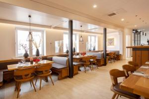 un restaurante con mesas y sillas de madera y ventanas en Hotel & Boarding House Schlosserwirt, en Mering