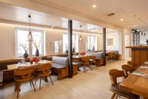 ein Restaurant mit Holztischen und -stühlen und Fenstern in der Unterkunft Hotel & Boarding House Schlosserwirt in Mering