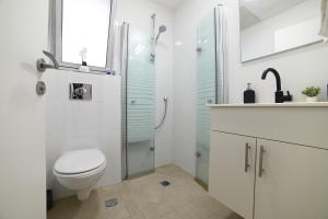 un bagno bianco con wc e doccia di וילה מארי עם בריכה במגדל a Migdal
