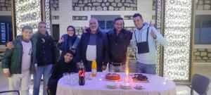Un groupe de personnes autour d'une table avec un gâteau dans l'établissement Relais Des Nomades, à Tinghir