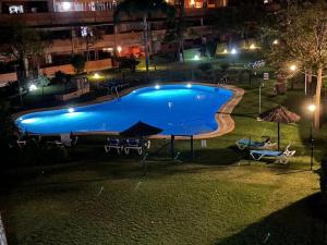 una gran piscina por la noche con mesas y sombrillas en Elviria Marbella Pinogolf en Marbella