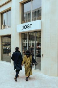 JOST Hôtel Bordeaux Centre Gare Saint Jean في بوردو: شخصان يسيران أمام متجر jlost