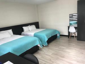 Habitación con 2 camas y una silla. en Floresta Inn Hotel, en Ambato