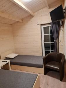 ein kleines Zimmer mit einem Bett und einem Stuhl in der Unterkunft Sodybos Narūnas namelis po egle 