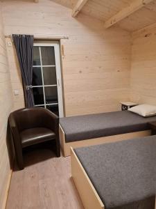 um pequeno quarto com 2 camas e uma cadeira em Sodybos Narūnas namelis po egle 