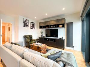 uma sala de estar com um sofá e uma televisão em Lovely 2 Bed Duplex Apartment with Hydro Views em Glasgow