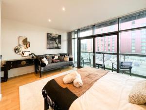 a bedroom with a bed and a couch and windows at Lovely 2 Bed Duplex Apartment with Hydro Views in Glasgow