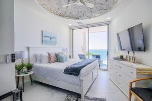 a white bedroom with a bed and a tv at Esmeralda Beach Resort in Puerto Peñasco