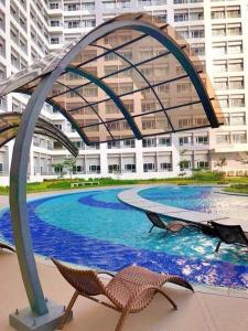 - une grande piscine avec 2 chaises devant un bâtiment dans l'établissement Modern Brand New Condo in Grace Residence Taguig, à Manille