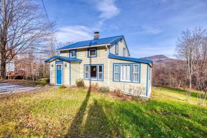 a yellow house with a blue roof on a grass field at Catskills Cottage with Deck, 7 Mi to Hunter Mtn in Elka Park