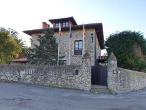 ein Steinhaus mit zwei Flaggen an einer Steinmauer in der Unterkunft Posada San Tirso in Toñanes