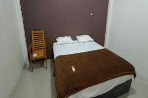 - une petite chambre avec un lit et une chaise dans l'établissement OYO 92243 Fanilly Guest House Marabahan, à Banjarmasin