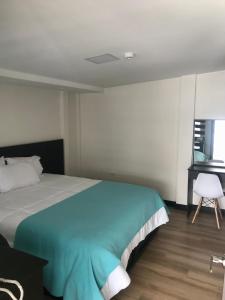 1 dormitorio con cama, escritorio y silla en Floresta Inn Hotel, en Ambato