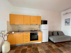 eine Küche mit orangefarbenen Schränken und einem Sofa in einem Zimmer in der Unterkunft Dammusi cala croce in Lampedusa