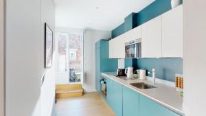 a kitchen with blue and white cabinets and a sink at L'Appart du Quai avec Terrasse in Strasbourg