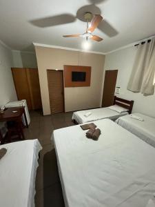 a hotel room with two beds and a ceiling fan at Hotel Portela II in Olímpia