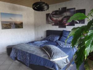 Schlafzimmer mit einem Bett mit blauer Bettwäsche und Plakaten in der Unterkunft Haus Eifelinchen in Schleiden