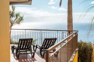 two chairs on a balcony looking out at the ocean at Palm Tree House in Câmara de Lobos