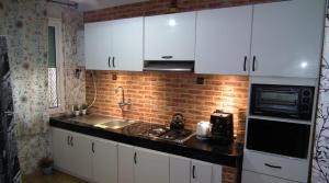 a kitchen with white cabinets and a brick wall at StayHere, Nice Apartment with Garden and sea view, 1 min walk From Beach, High-Speed WI-FI in El Jadida