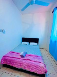 Bella Homestay Beaufort Sabah في بوفورت: غرفة نوم بسرير وبطانية وردية