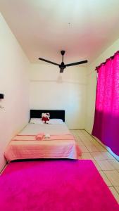 Bella Homestay Beaufort Sabah في بوفورت: غرفة نوم مع سرير وردي مع مروحة سقف