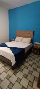 a bedroom with a large bed with a blue wall at Pousada do Luar Cabo Frio in Cabo Frio