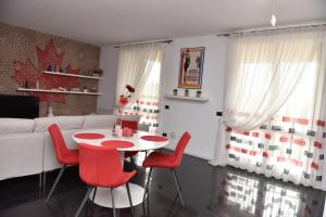 a living room with a table and red chairs at Design & Comfort a Romano di L. in Romano di Lombardia