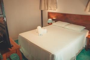1 dormitorio con 1 cama blanca y TV en Pousada Hannah, en Prado