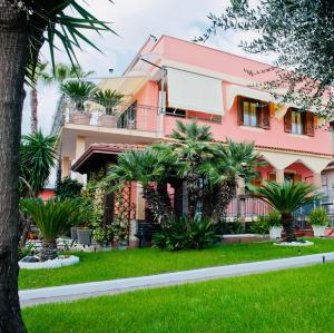 une maison rose avec des palmiers devant elle dans l'établissement Ottaviano B&B, à Ottaviano