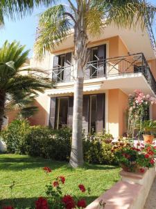 a house with a palm tree and flowers in front of it at Appartamento in Villa a circa 100 metri dal mare in Fontane Bianche