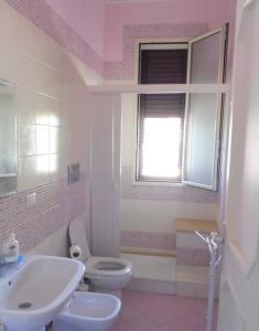 a bathroom with a sink and a toilet and a window at Appartamento in Villa a circa 100 metri dal mare in Fontane Bianche
