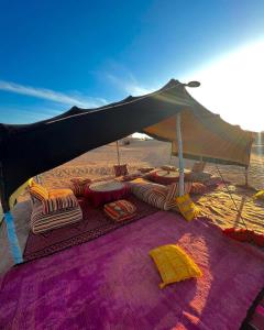 a tent on the beach with chairs and pillows at Bivouac Luna in Mhamid