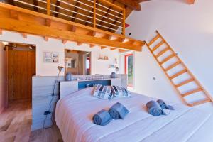ein Schlafzimmer mit einem großen weißen Bett mit blauen Kissen in der Unterkunft Sierra Melides Alentejo - Sun, Nature & Sea in São Francisco da Serra