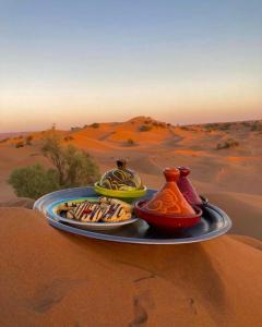 a tray with three vases on a plate in the desert at Bivouac Luna in Mhamid