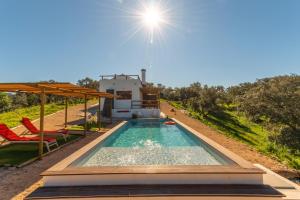 una piscina con tavolo e sedie e una casa di Sierra Melides Alentejo - Sun, Nature & Sea a São Francisco da Serra