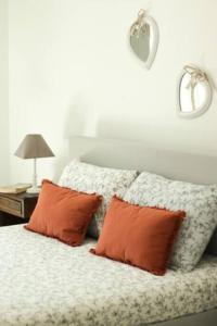 uma cama com duas almofadas laranjas em cima em A Casa do Tio Joaquim em Montemor-o-Novo