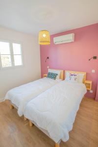 a large white bed in a room with a pink wall at LE VAISSEAU Maison avec piscine/parking/wifi/plages 5kms in Les Mathes