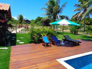 a wooden deck with two chairs and an umbrella at Villa Angelim - Natureza e Conforto Barra do Cunhaú in Barra do Cunhau