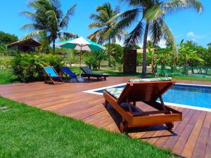 una terraza de madera con sillas y una piscina en Villa Angelim - Natureza e Conforto Barra do Cunhaú, en Barra do Cunhau