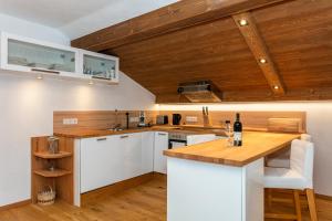 cocina con armarios blancos y techo de madera en Ferienwohnung Herbst, en Unken