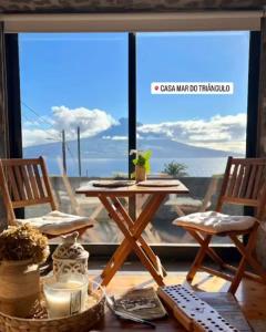 a table and two chairs in front of a window at Casa Mar do Triângulo in Horta