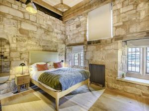 um quarto com uma cama numa parede de pedra em Swanswell Gate em Coventry