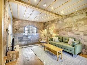 uma sala de estar com um sofá verde e uma parede de pedra em Swanswell Gate em Coventry